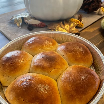 Six golden dinner rolls in a foil pan
